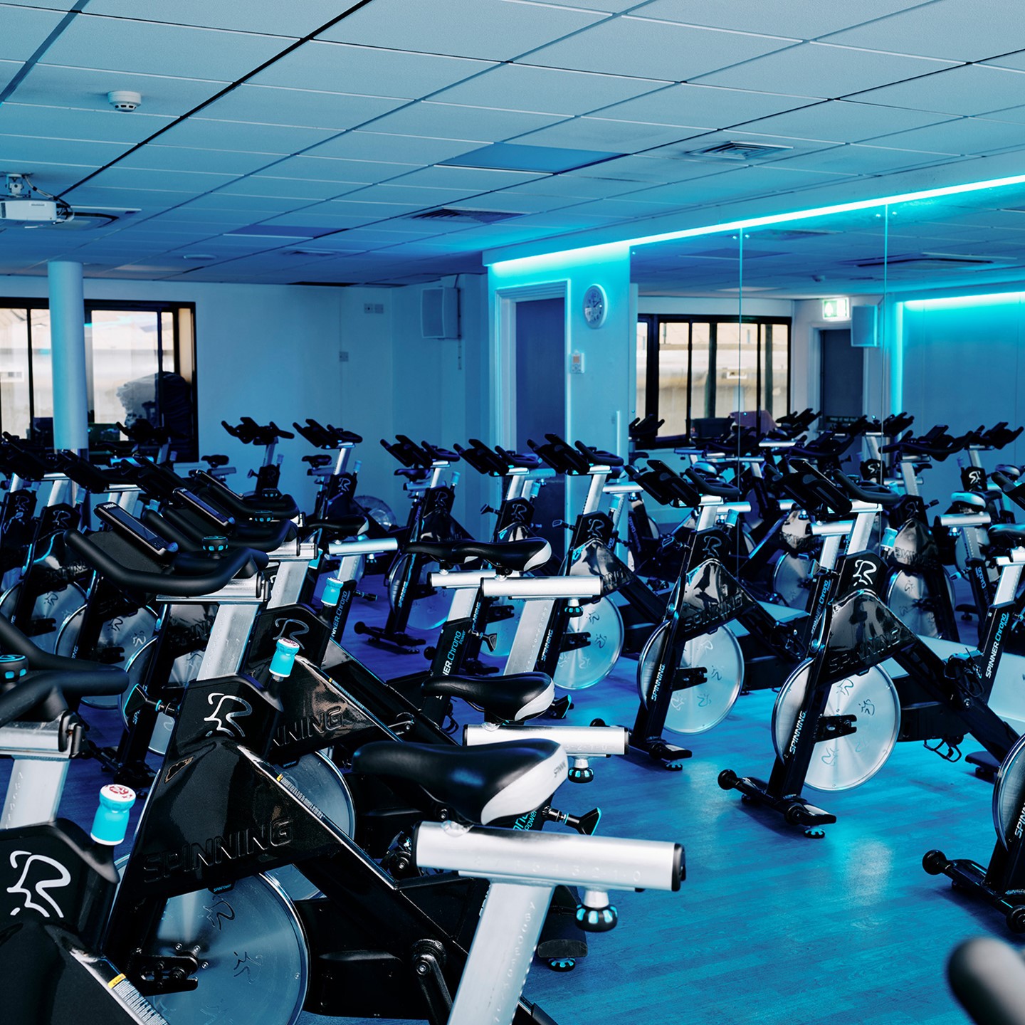 Room full of spinning bikes with blue lights