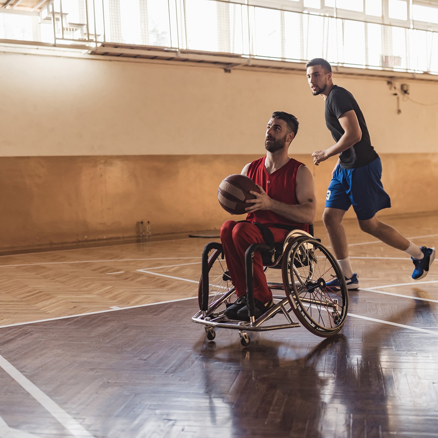 Two men playing basketball, one in a wheelchair
