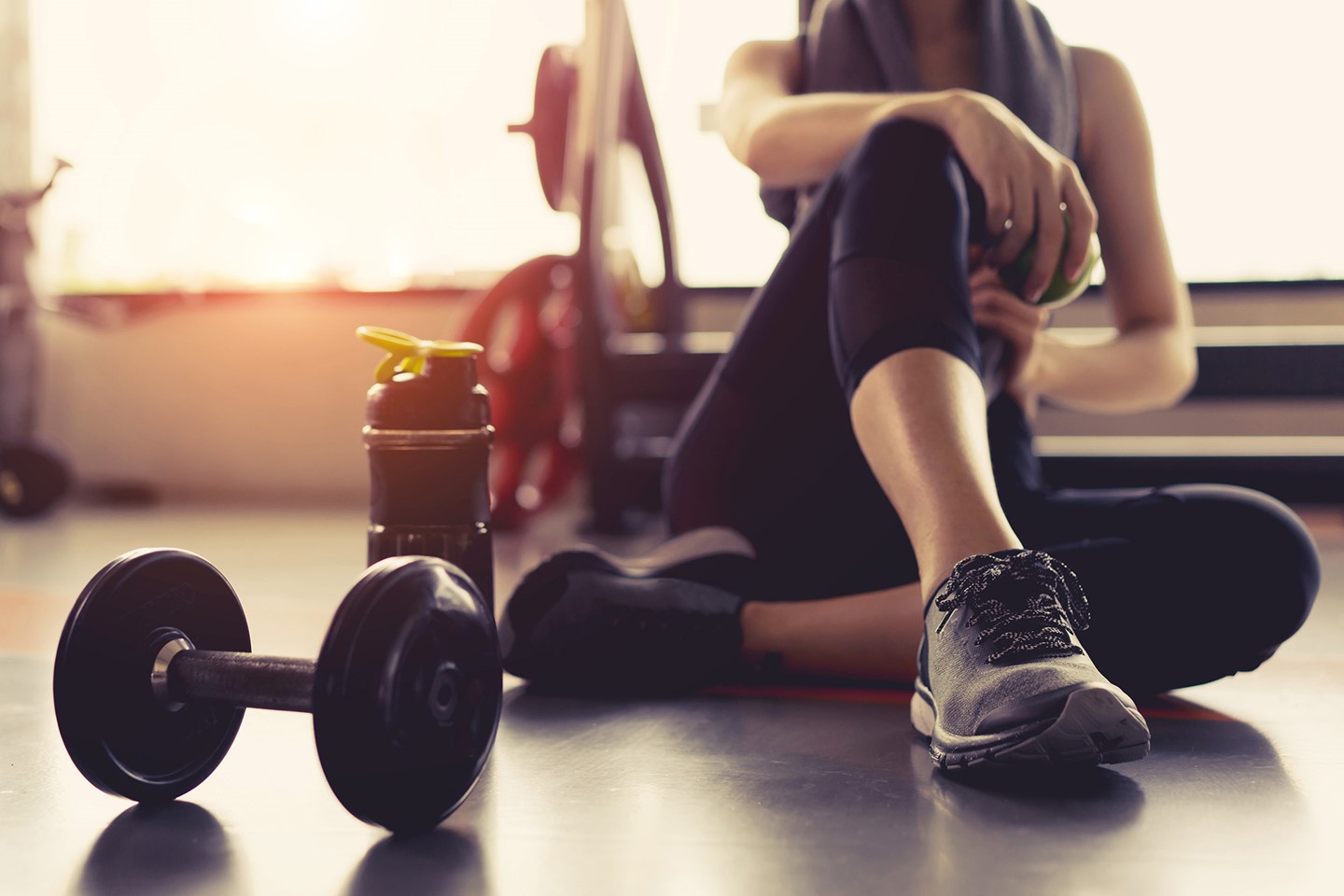 Woman sitting on the floor next to gym equipment 