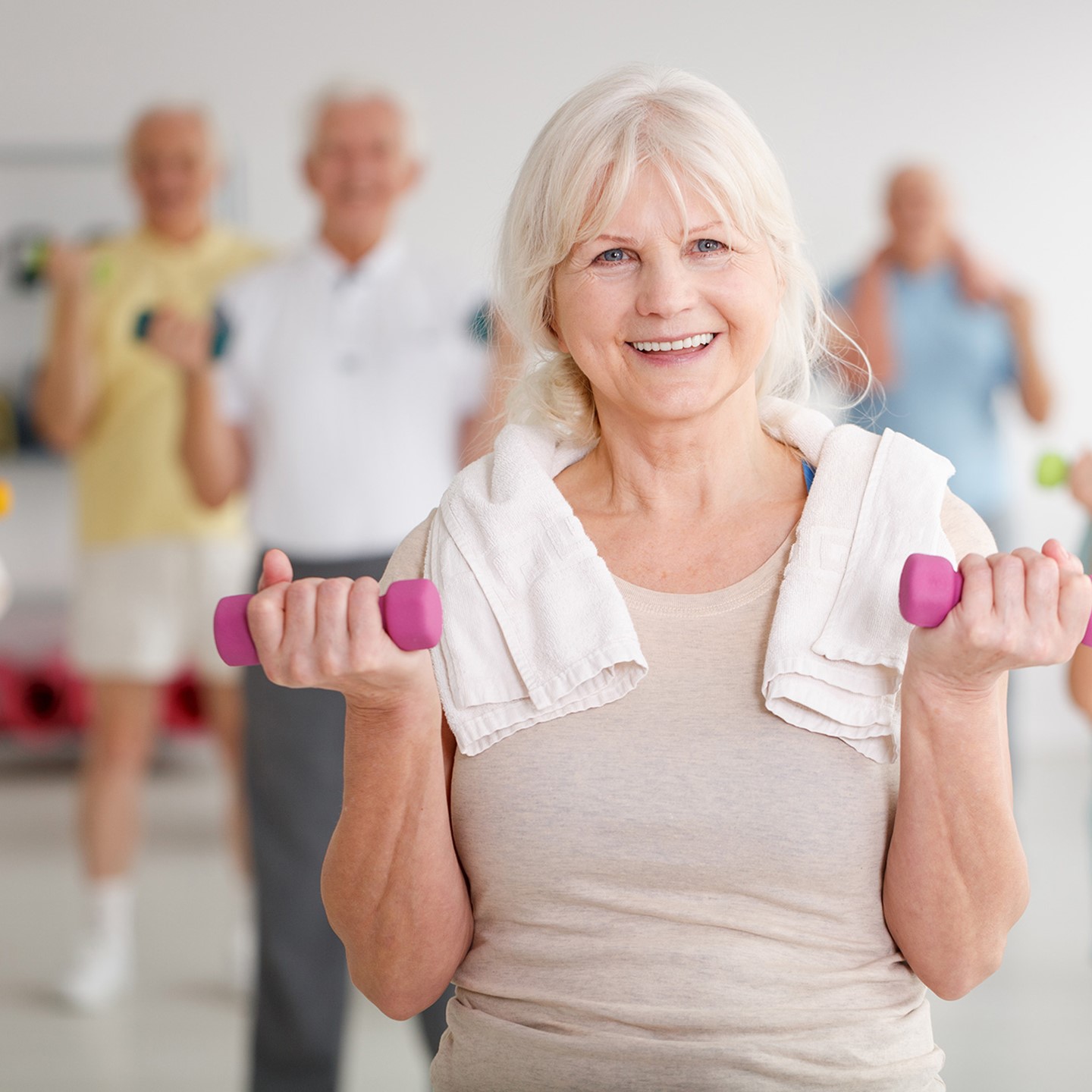 Group of adults lifting dumbbells in fitness class